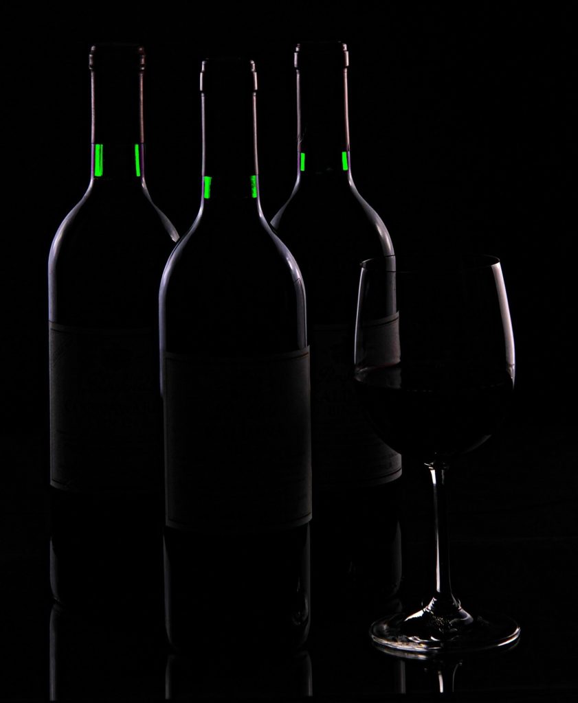 Three bottles and a wine glass in shadow